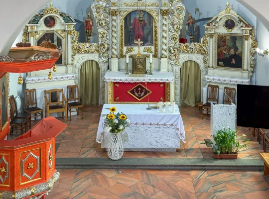 Widok na prezbiterium kościoła parafialnego z ołtarzami i amboną.